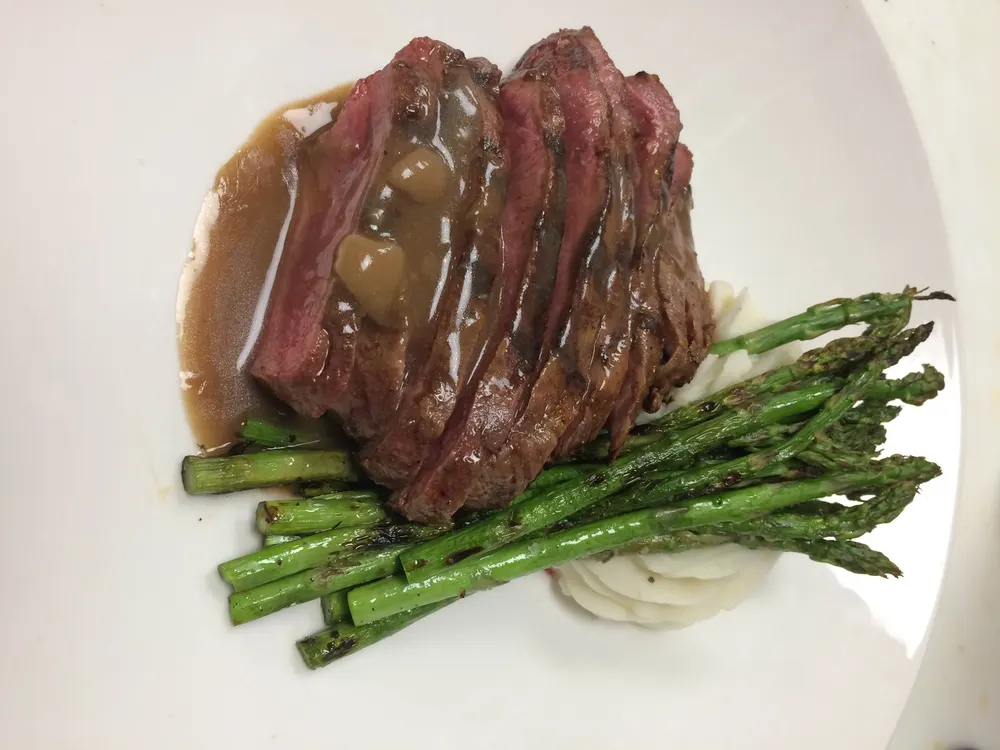 Sliced flat iron steak over asparagus with a mushroom sauce