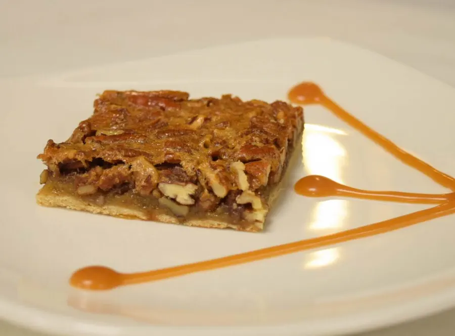 A pecan tart served with caramel sauce
